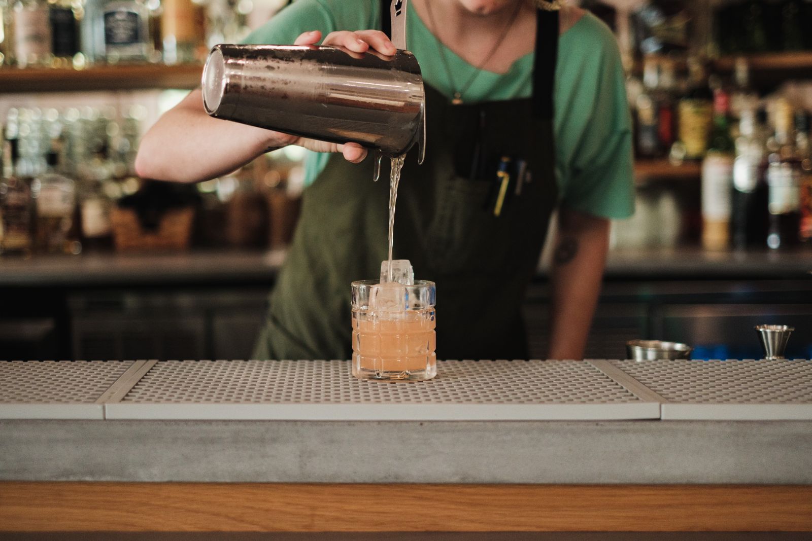 Bartender preparando un cóctel con una coctelera en la barra